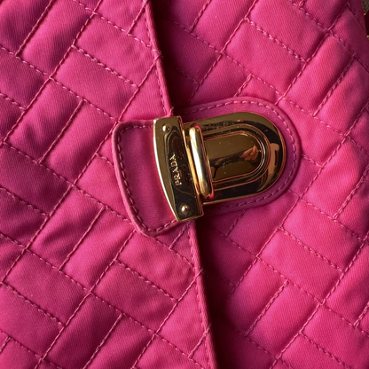 Close-up of a pink quilted handbag with a gold Prada clasp.