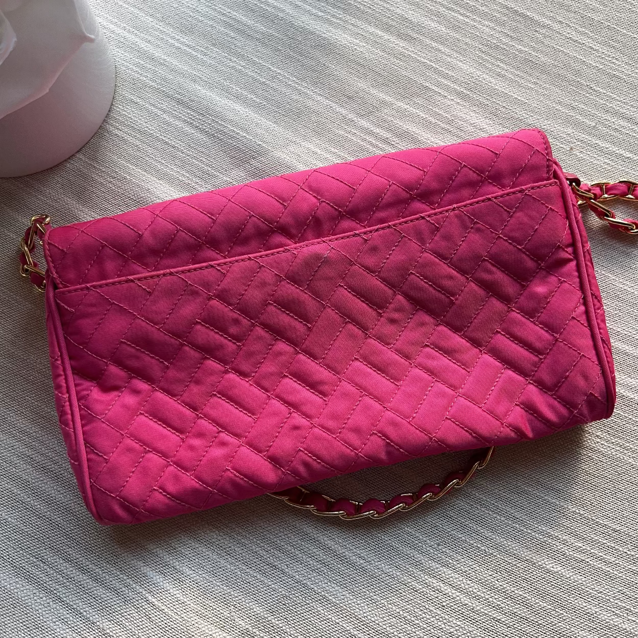 Pink quilted clutch bag on a textured surface