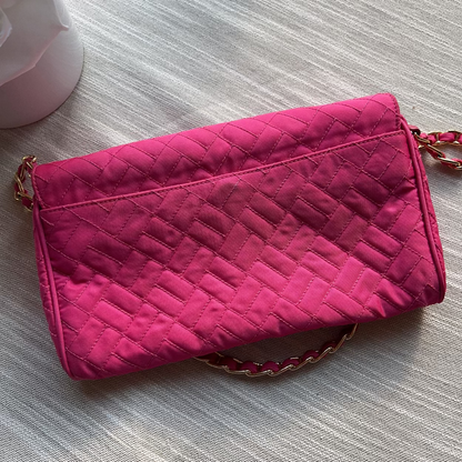 Pink quilted clutch bag on a textured surface