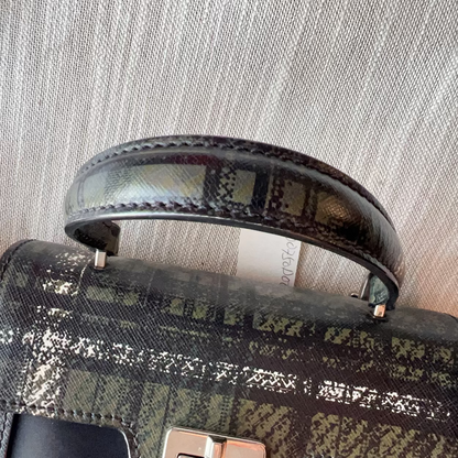 Patterned handbag with a textured handle on a neutral background