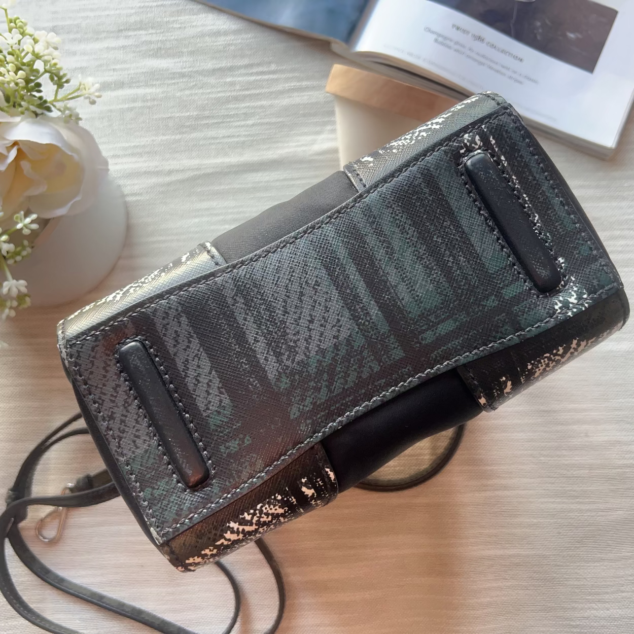 Patterned wallet with strap on a light wooden surface