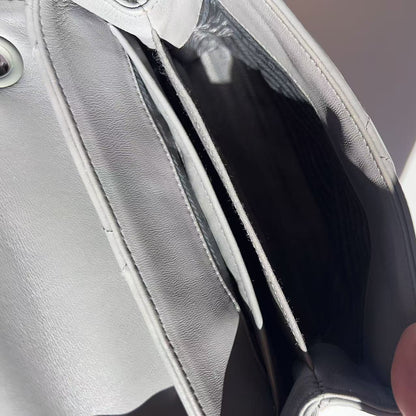 Close-up of a hand holding a silver clutch bag with a blurred background