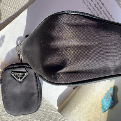 Black Prada pouch and small gray pouch on a textured surface