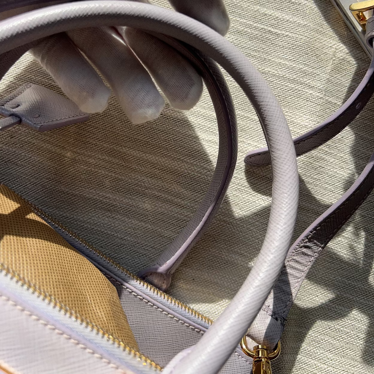 Close-up of a light gray handbag strap with a textured surface.