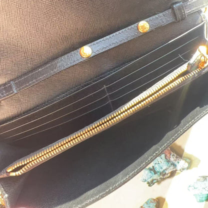 Close-up of a black textured leather or canvas wallet with multiple card slots, a zippered compartment, and gold-tone hardware.