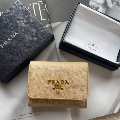 A beige Prada Saffiano wallet with a gold-tone logo, displayed with its black textured presentation box and white interior box on white paper packaging.