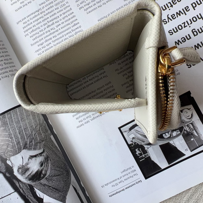 A cream-colored canvas zippered pouch with a gold zipper, shown open and resting on top of an open book.