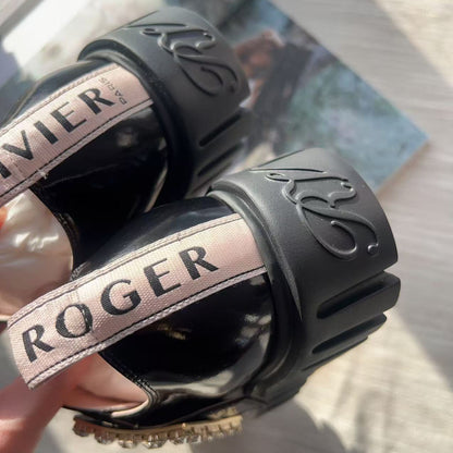 Black leather gloves with 'Roger' and 'Xavier' branding on a magazine background