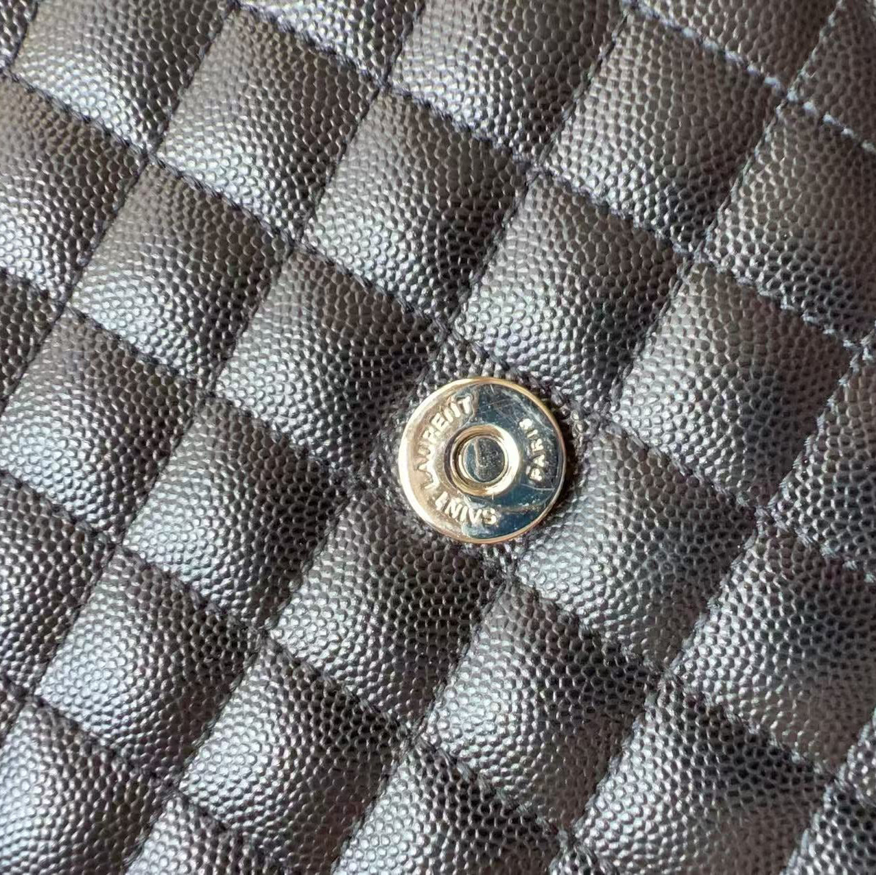 Close-up of a black quilted caviar leather bag with a silver-tone metal snap button.