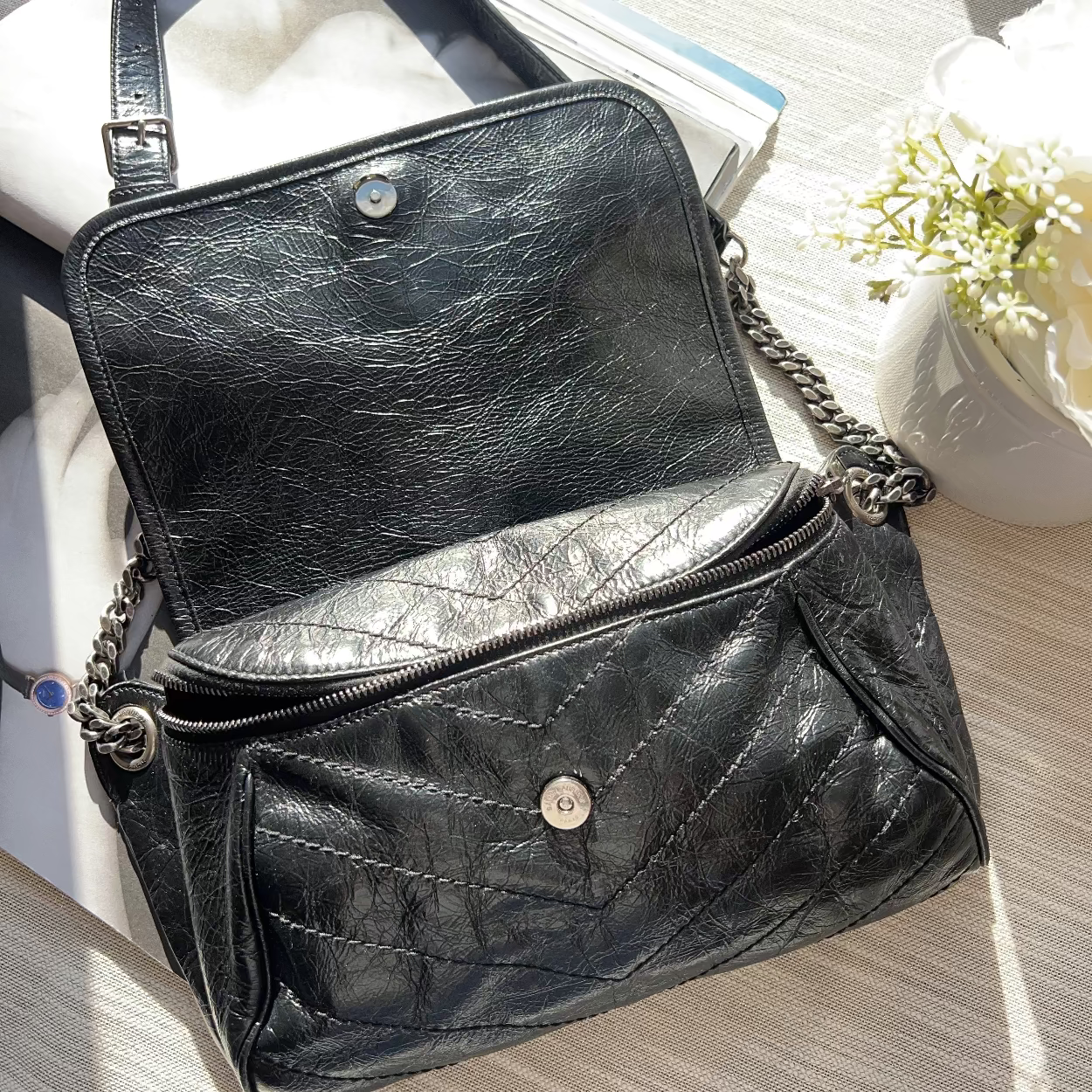Black leather handbag with chain detail on a light surface