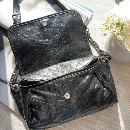 Black leather handbag with chain detail on a light surface