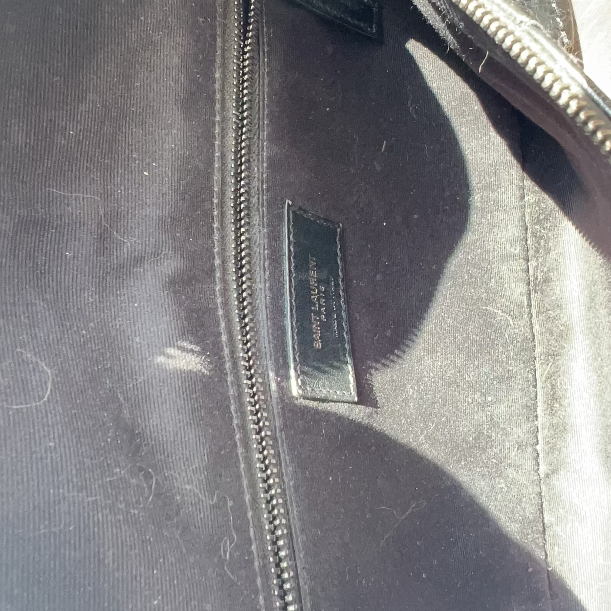 Close-up of a black leather jacket with a zipper and visible brand label.