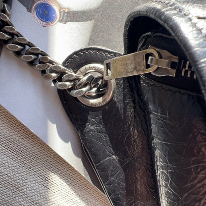 Close-up of a leather handbag with a chain detail on a mannequin.