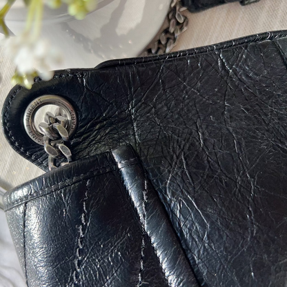 Close-up of a black leather wallet with a silver clasp on a light background.