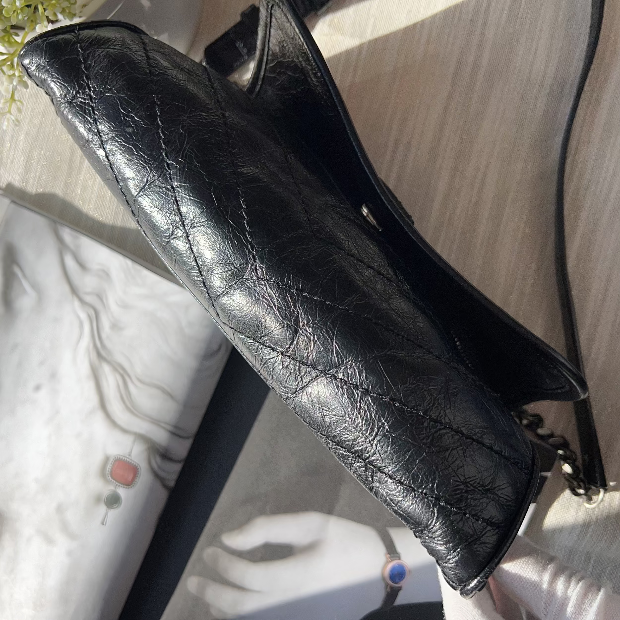 Black leather clutch on a light surface with a blurred background