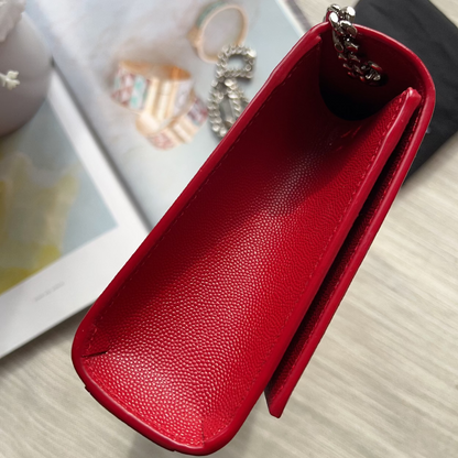 Red leather pouch with a chain on a light wooden surface