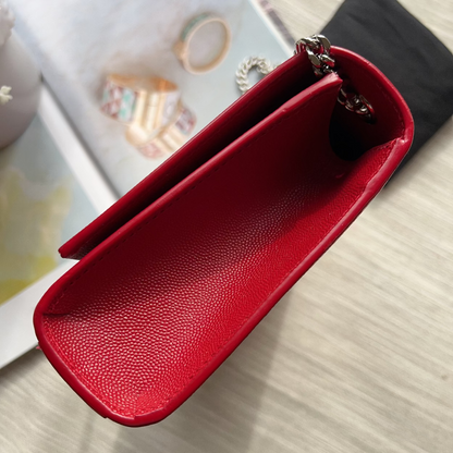 Red leather pouch on a light wooden surface with blurred jewelry in the background