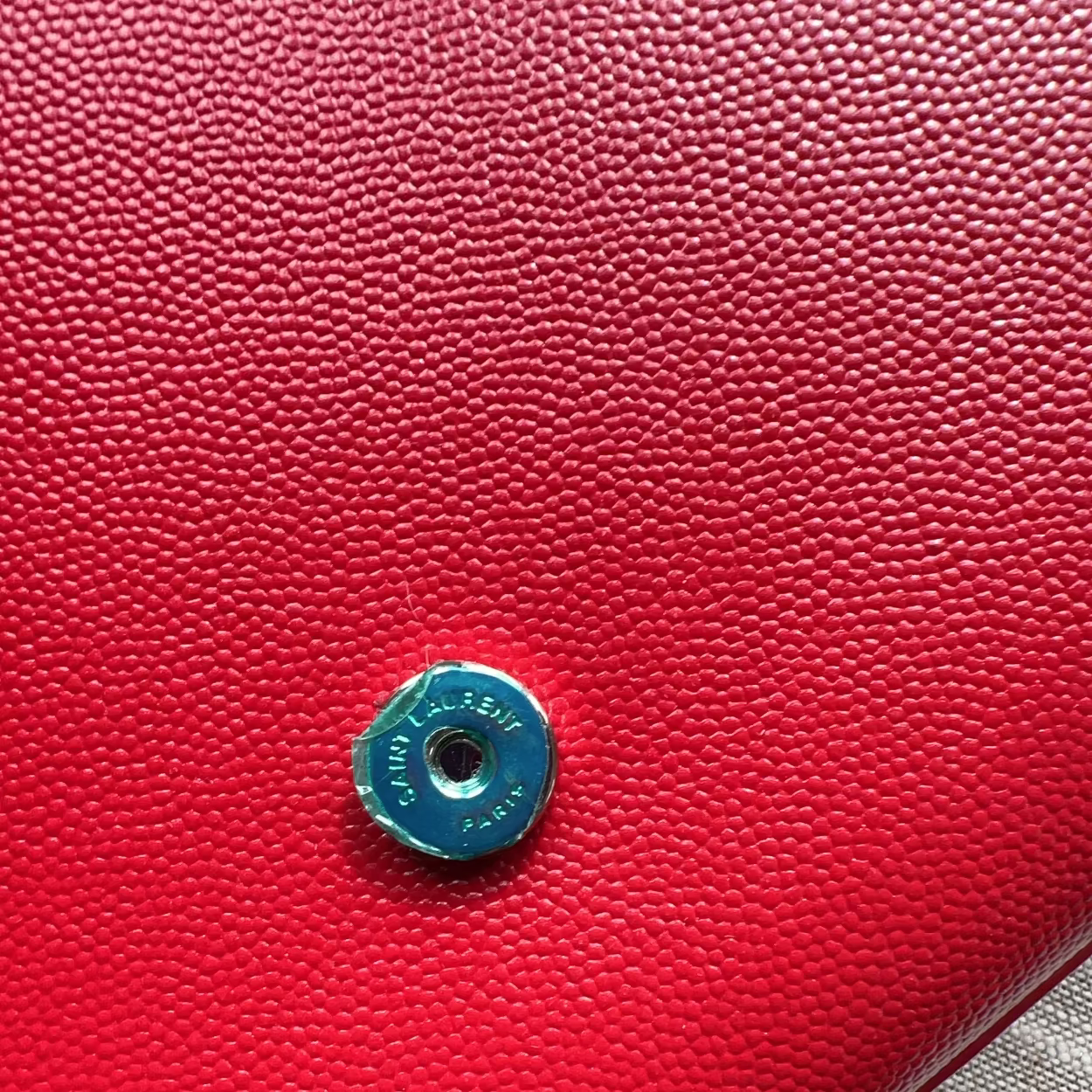Close-up of a red textured surface with a blue metal button featuring 'Johnstons of Elgin' branding.