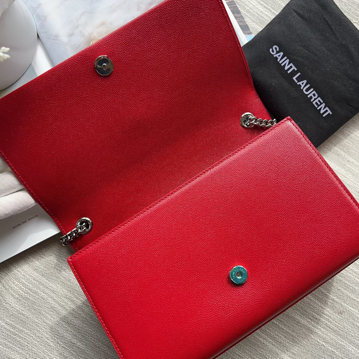 Red wallet with a black Saint Laurent pouch on a light gray surface