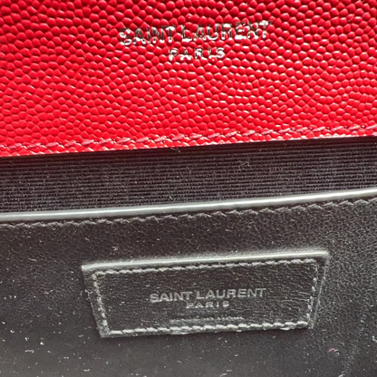 Close-up of a red and black Saint Laurent handbag with visible branding.