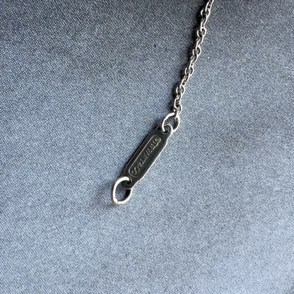 Silver bottle opener with chain on a textured gray background