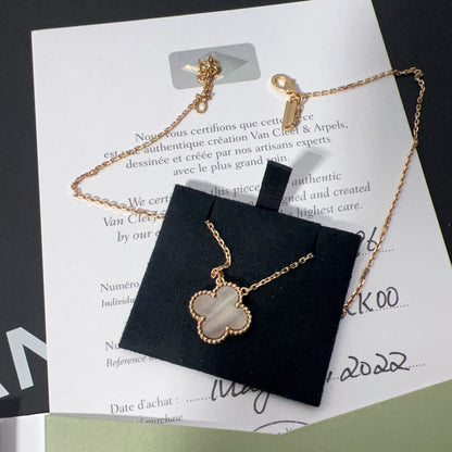Gold necklace with a clover pendant on a branded card