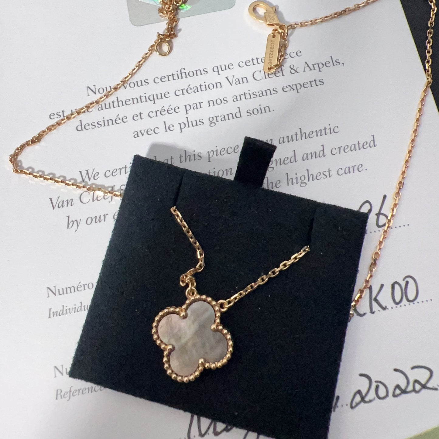 Gold necklace with a clover-shaped pendant on a branded card