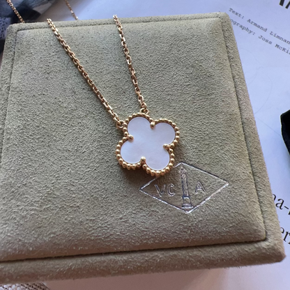 Gold necklace with a clover pendant on a MCA branded box