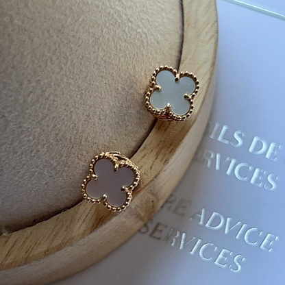 Clover-shaped earrings on a wooden stand with a blurred background