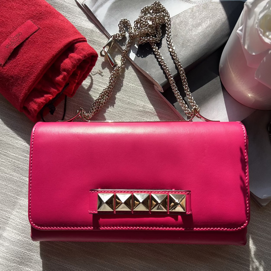 Pink wallet with studded detail on a light gray surface