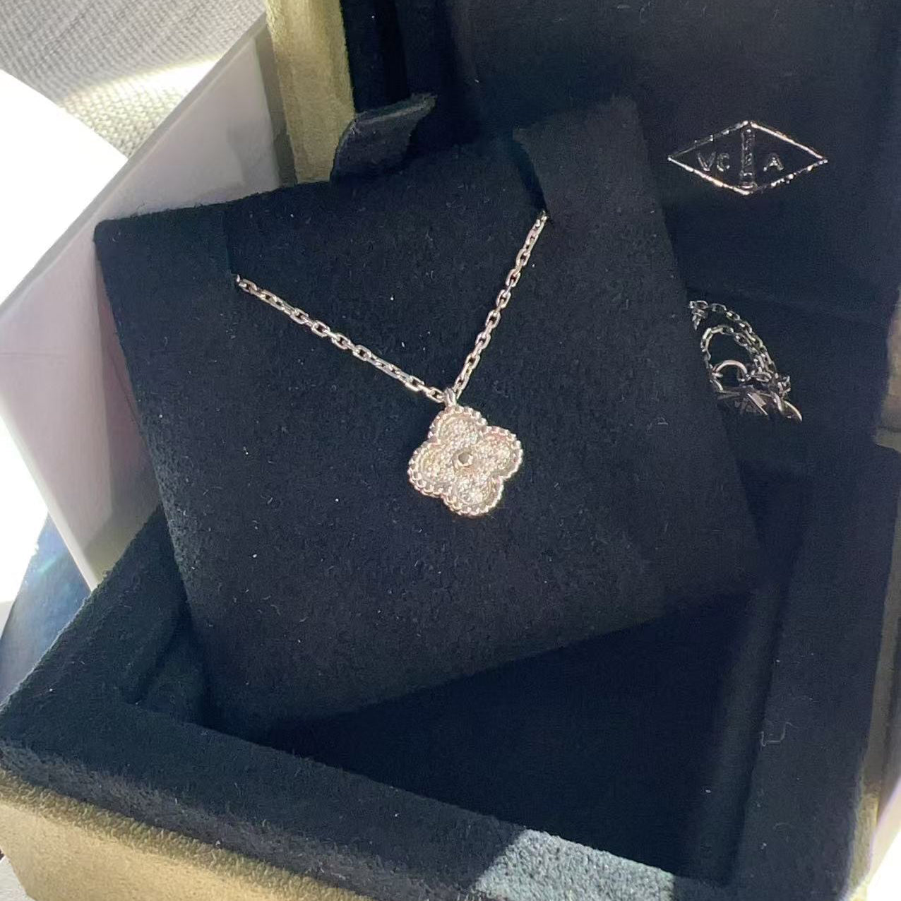 Silver necklace with a floral pendant on a black jewelry box