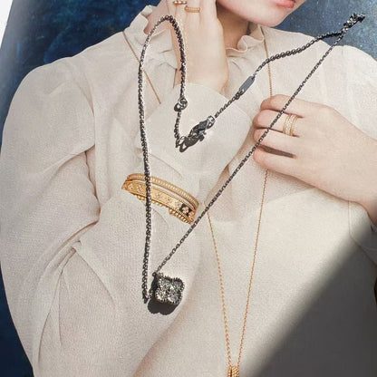Person wearing a beige outfit with jewelry including necklaces and rings.