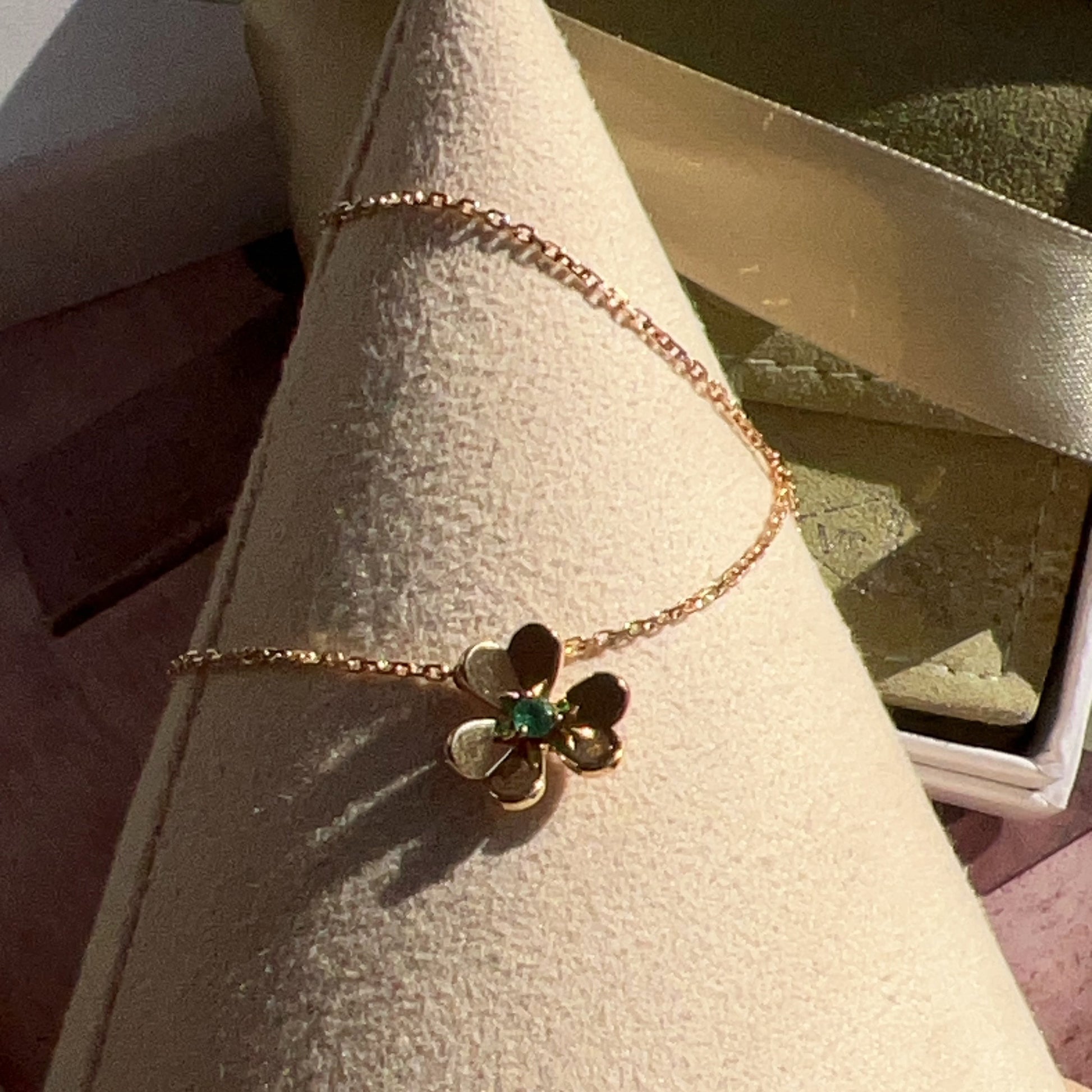 Gold bracelet with a flower-shaped clasp on a cone-shaped display stand.