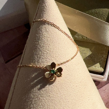Gold bracelet with a flower-shaped clasp on a cone-shaped display stand.