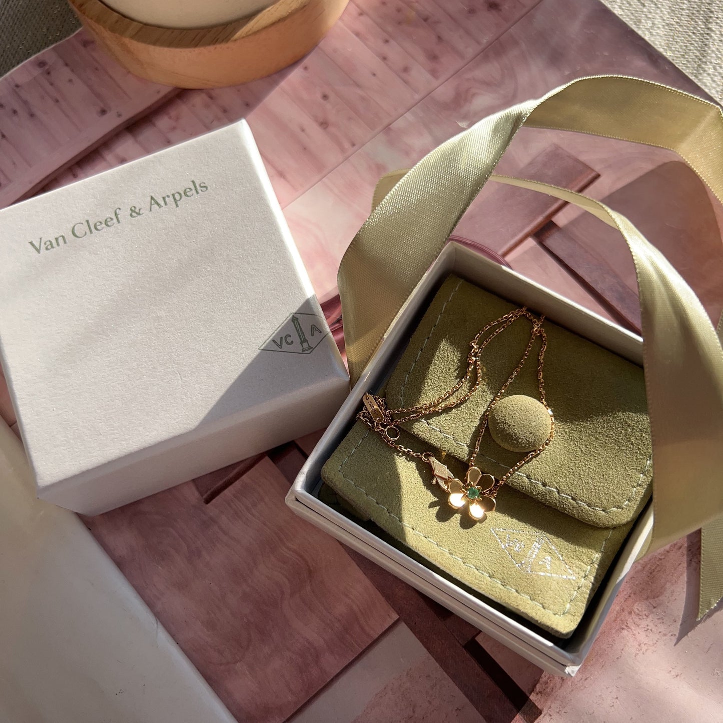 Green jewelry box with a necklace on a pink surface