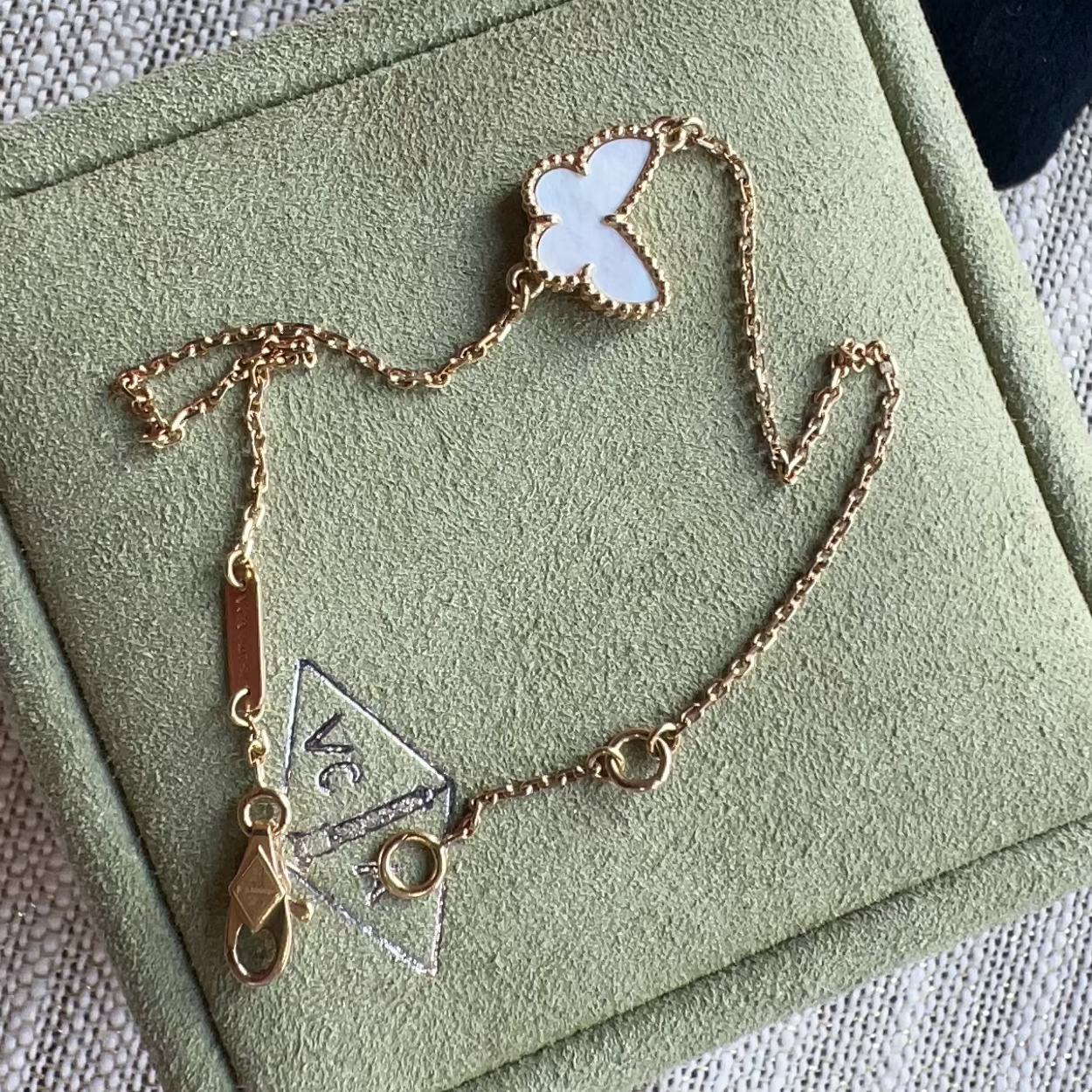 Gold necklace with butterfly pendant on a green jewelry box
