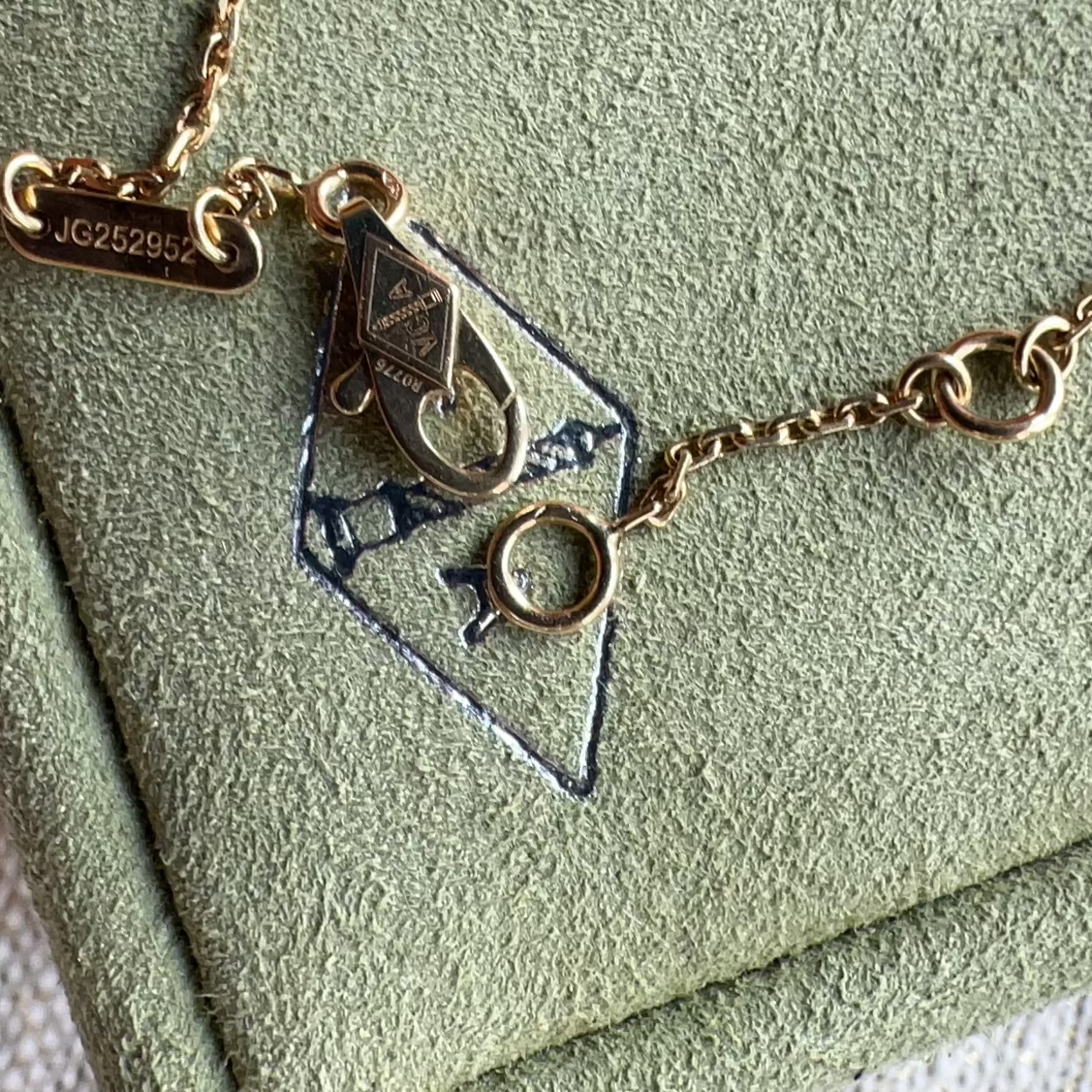 Gold necklace with a geometric pendant on a green textured surface
