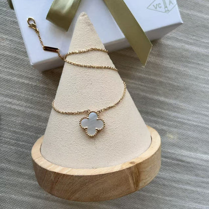 Necklace with a clover-shaped pendant on a wooden stand, with a gift box in the background.