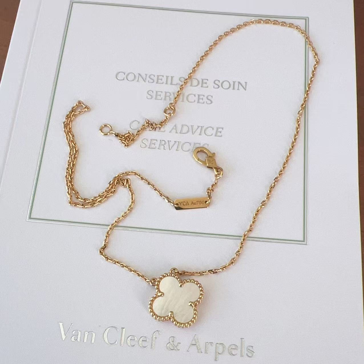 Gold necklace with a clover-shaped pendant on a Van Cleef & Arpels card.