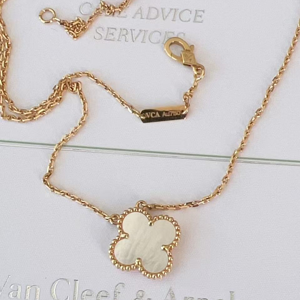 Gold necklace with a clover-shaped pendant on a white background