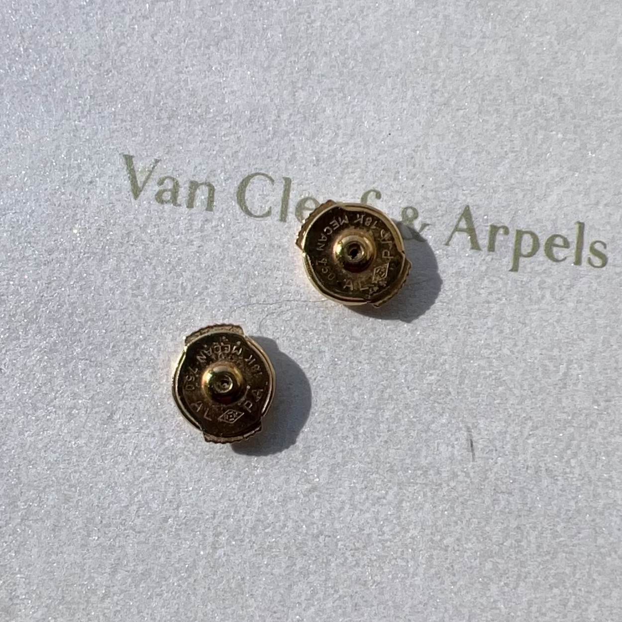 Gold earrings on a Van Cleef & Arpels branded card