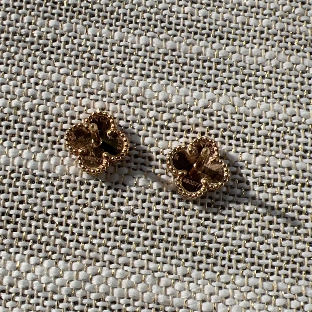 Pair of gold earrings on a textured fabric background