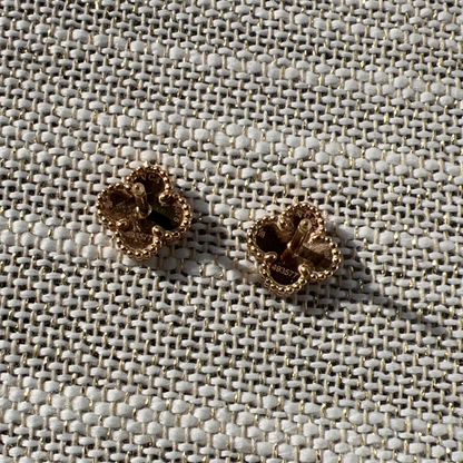Pair of gold earrings on a textured fabric background