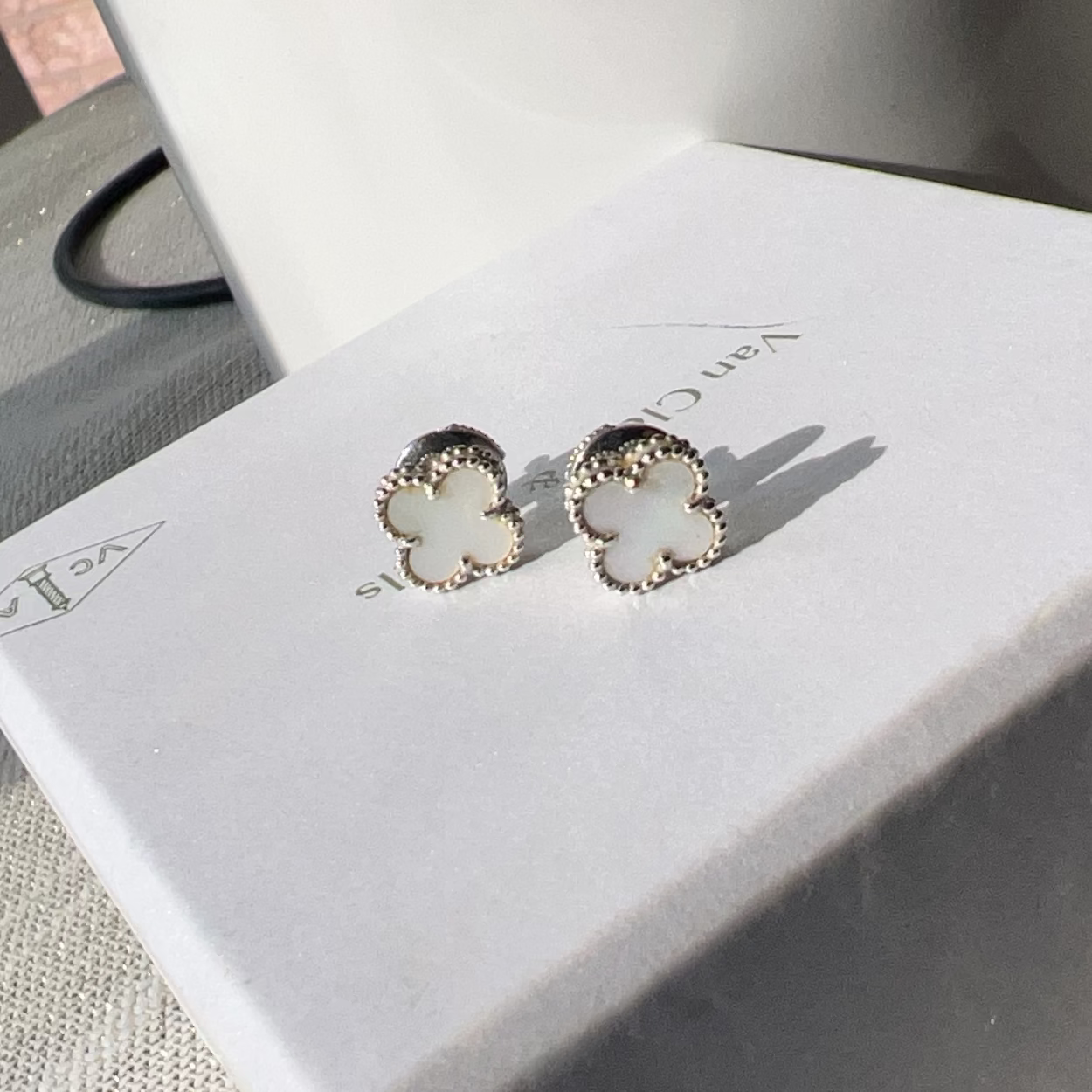 Pair of earrings on a white box with a brand name.