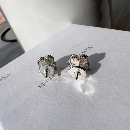 Silver earrings on a white box with 'Vancleef & Arpels' branding.