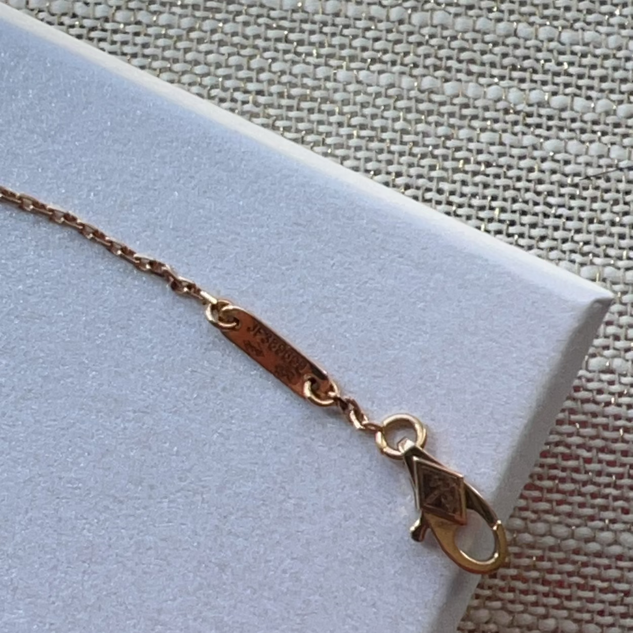 Gold bracelet on a light blue cushion with a textured beige background