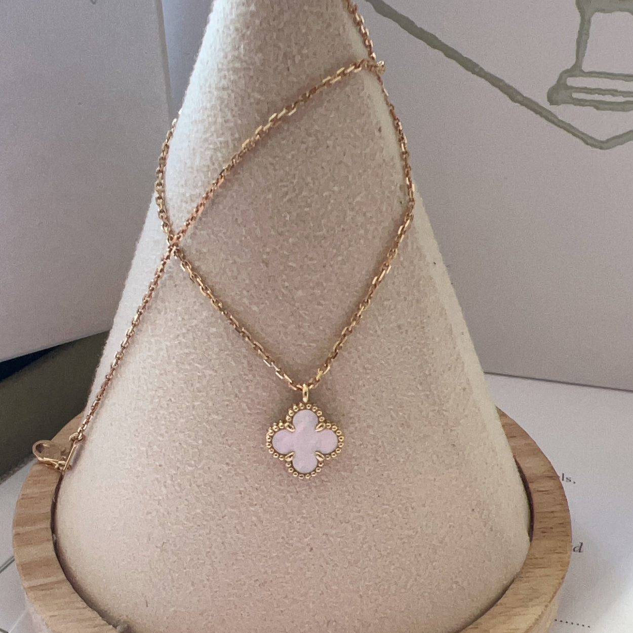 Necklace with a pink clover pendant on a wooden stand