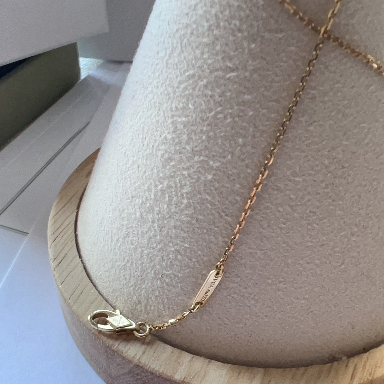 Gold necklace on a wooden stand with a white background