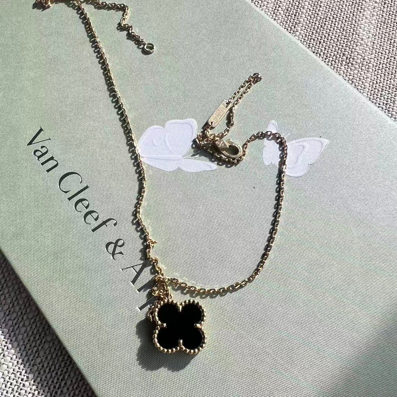 Van Cleef & Arpels necklace with a black clover pendant on a light green background