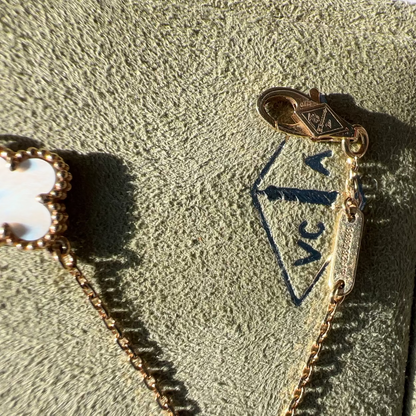 Close-up of a gold-tone jewelry clasp and chain attached to a textured olive-green jewelry box, with part of a flower-shaped charm visible on the left.